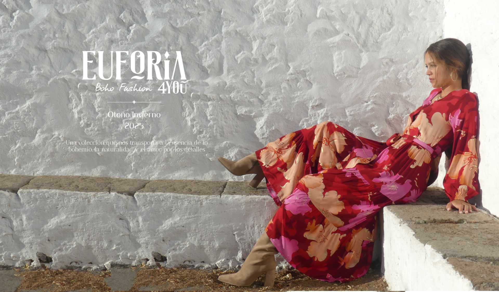 Imagen de mujer joven sentada en banco de piedra con un vestido de estilo boho chic, de estampado de flores grandes, en tonos camel y rojos, con detalles de lurex dorado