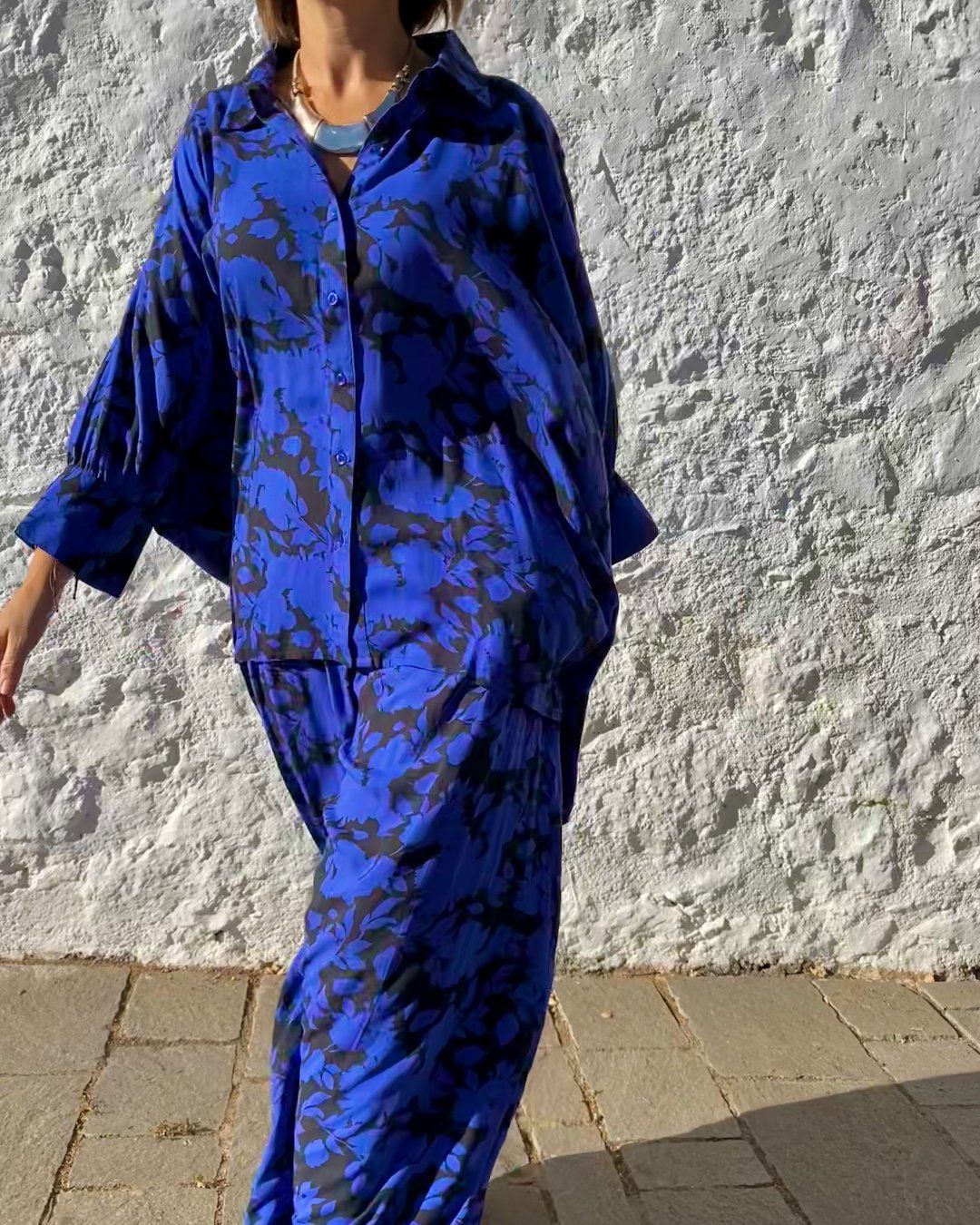Mujer vestida con conjunto oversize de blusón y palazzo, estampado en fondo azulón y dibujos en negro, de esencia boho chic