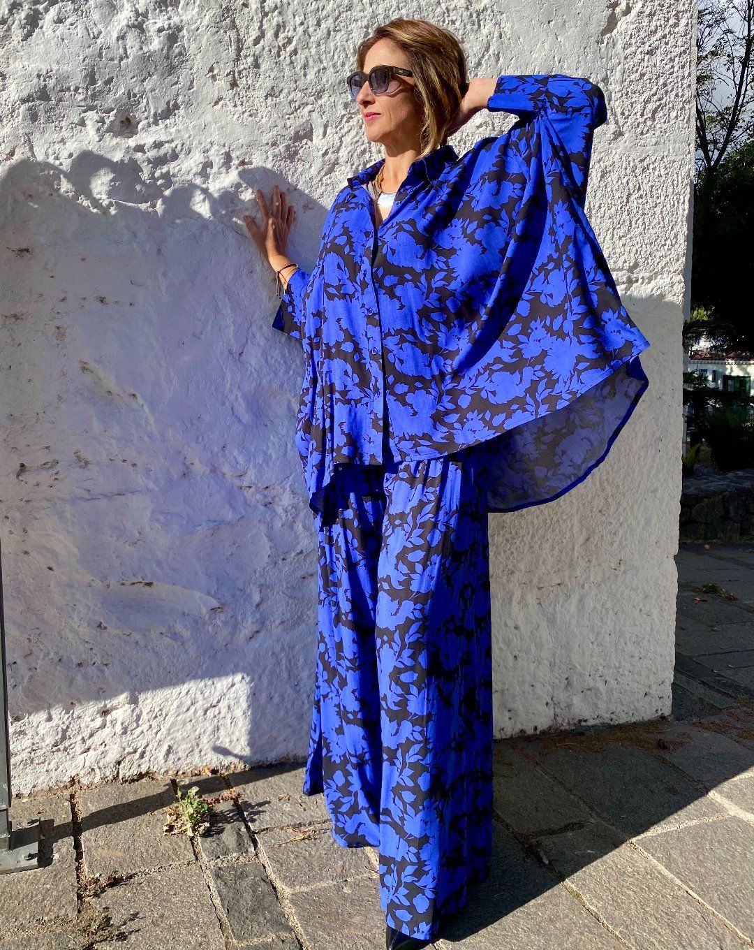Mujer vestida con conjunto oversize de blusón y palazzo, estampado en fondo azulón y dibujos en negro, de esencia boho chic