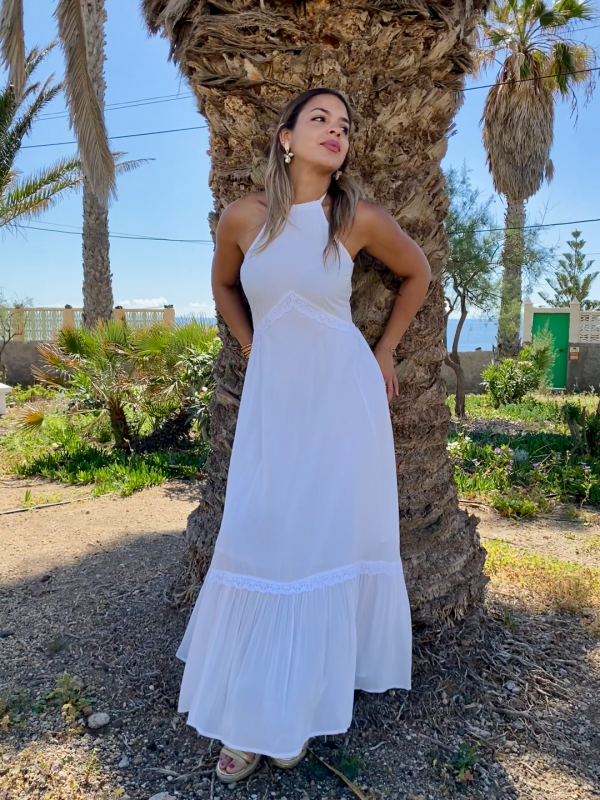 Mujer joven rubia con vestido largo blanco de estilo ibicenco boho chic, cuello Halter y espalda descubierta.