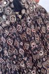 Detalle del tejido y la cintura bordada de falda de gasa en tonos oscuros, de estampado ikat, de estilo boho chic, étnico