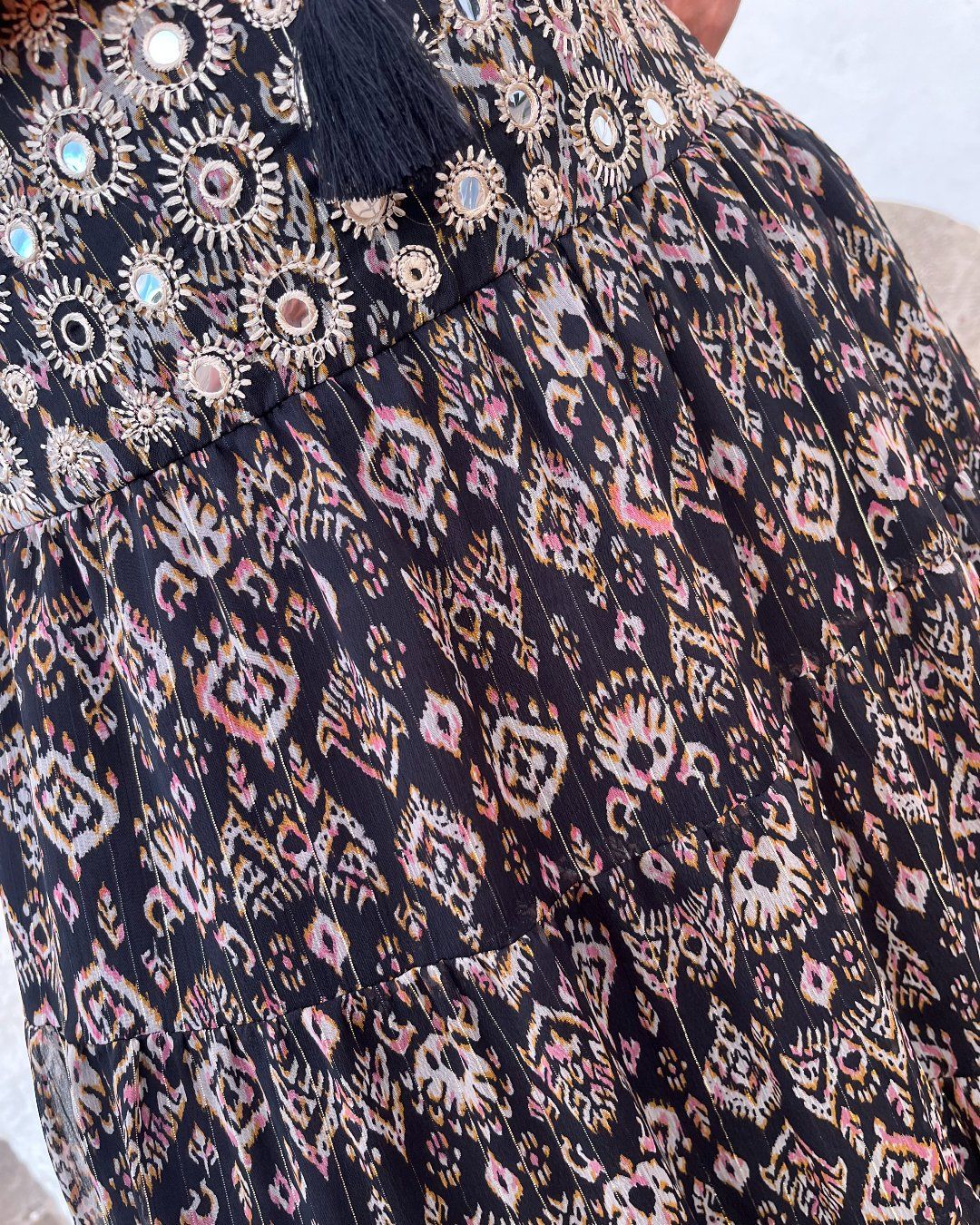 Detalle del tejido y la cintura bordada de falda de gasa en tonos oscuros, de estampado ikat, de estilo boho chic, étnico