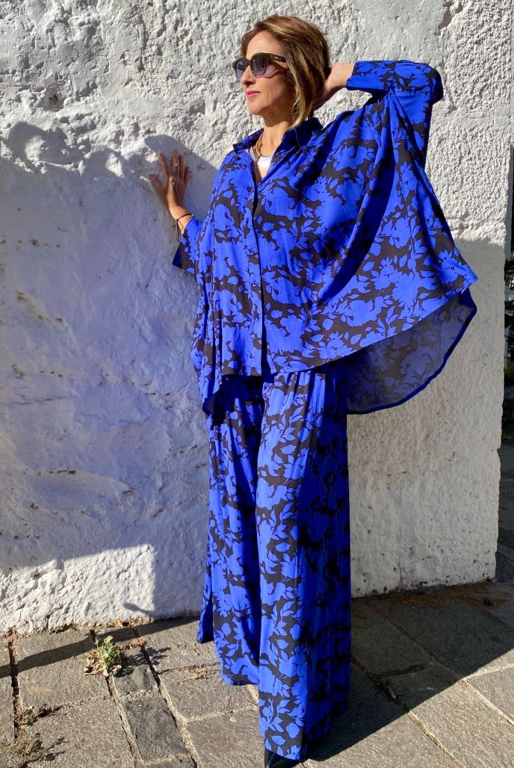 Mujer vestida con conjunto oversize de blusón y palazzo, estampado en fondo azulón y dibujos en negro, de esencia boho chic