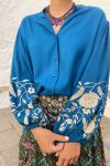 Blusa fluida de color azul, abotonada, de mangas globo largas, con bordados de flores en tono crudo