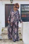 Mujer vestida con conjunto oversize de blusón y palazzo, con estampado de paisleys en tonos nude sobre negro, de esencia boho chic